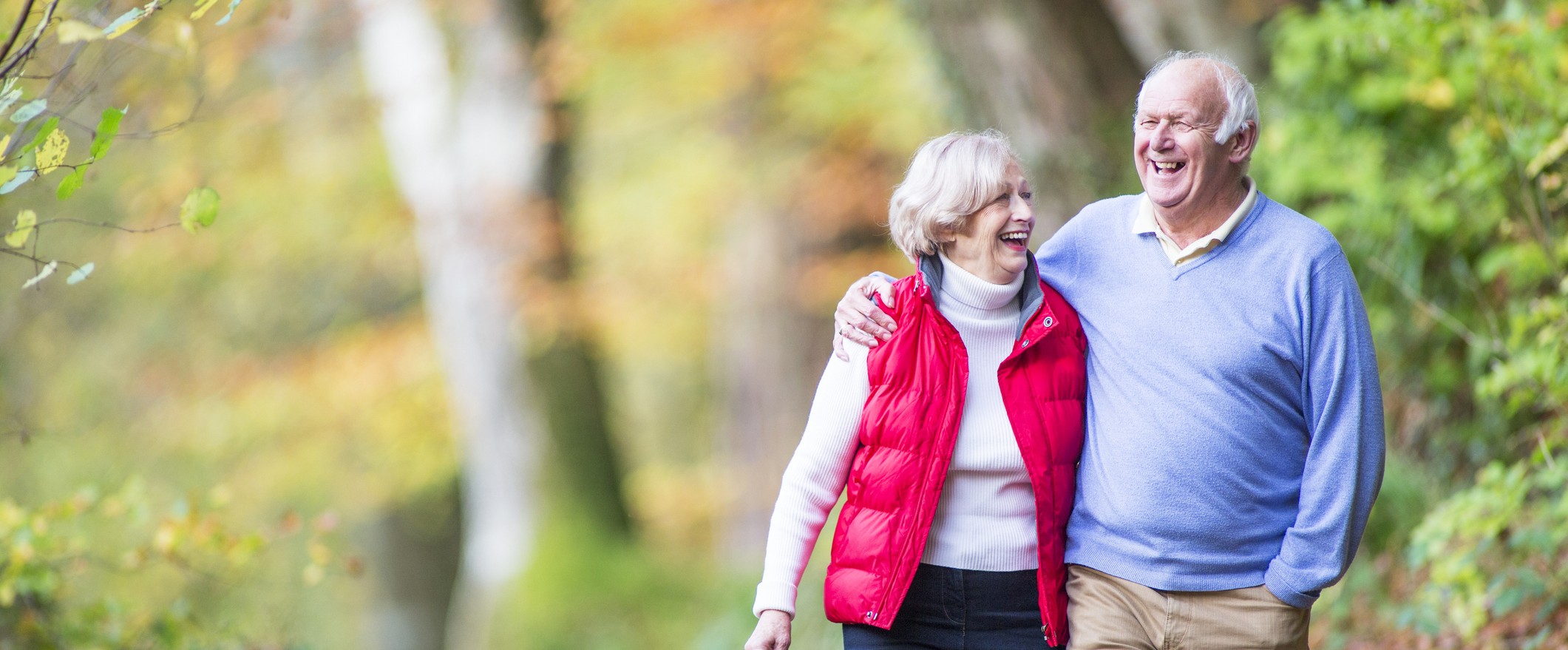 Older couple walking through trees.